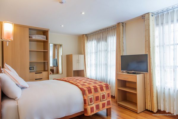 Habitación matrimonial con televisor y escritorio